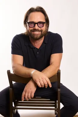 <p>homme souriant assis sur une chaise</p>
