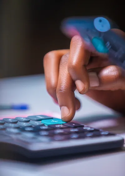 close-up Virtical photo of brown Dark skinned African person hand fingers punching pressing calculator on white table desk