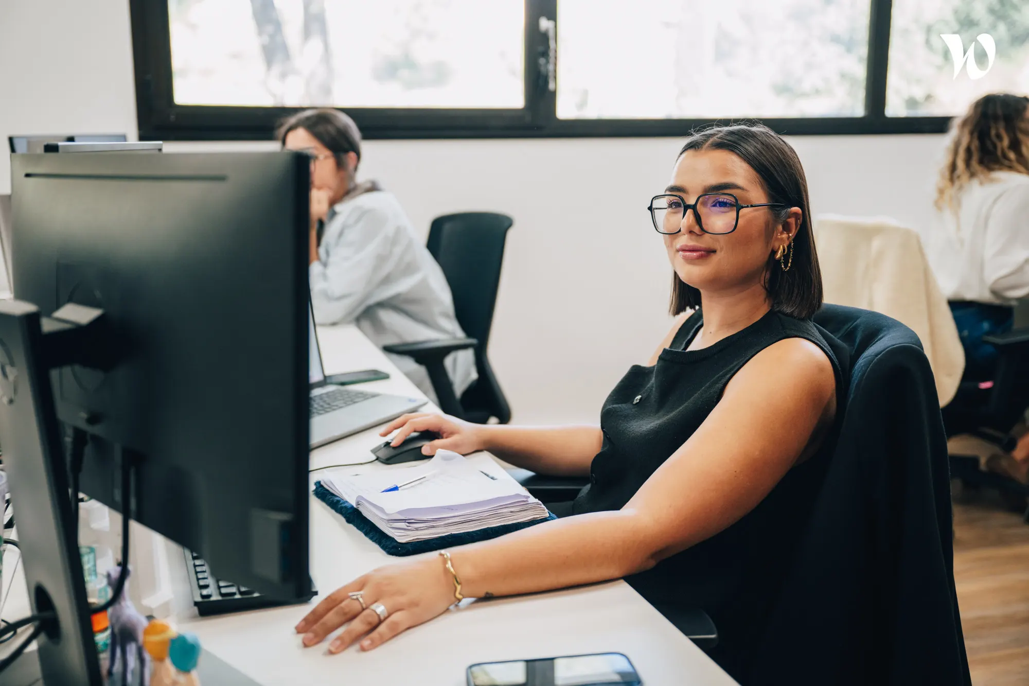 <p>jeune femme assise à son bureau qui travaille</p>

